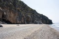 A cavernous cliff behind a sandy beach. Cove. Royalty Free Stock Photo